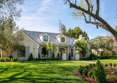 Elegant stone house with a manicured lawn and lush greenery.