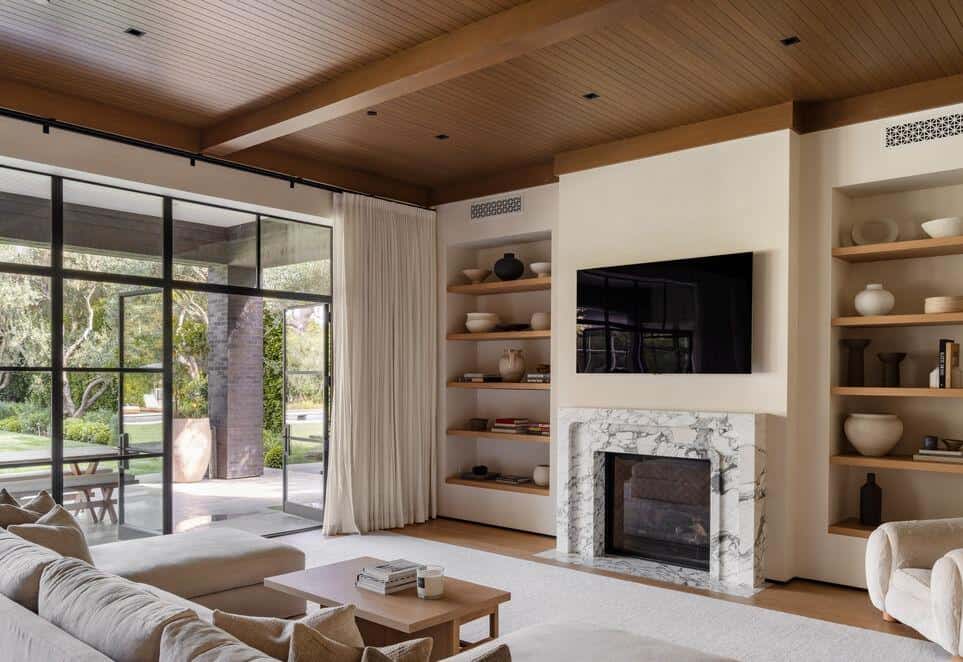 Contemporary living room featuring a fireplace, built-in shelves, and large glass doors opening to o.
