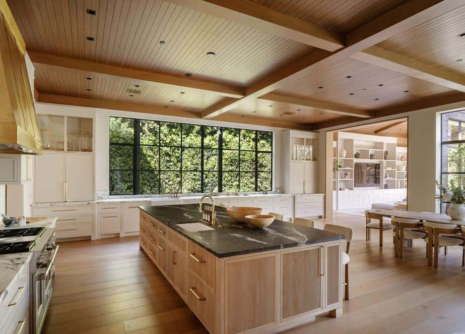 Spacious kitchen featuring large windows, natural wood finishes, and a central island for cooking an.