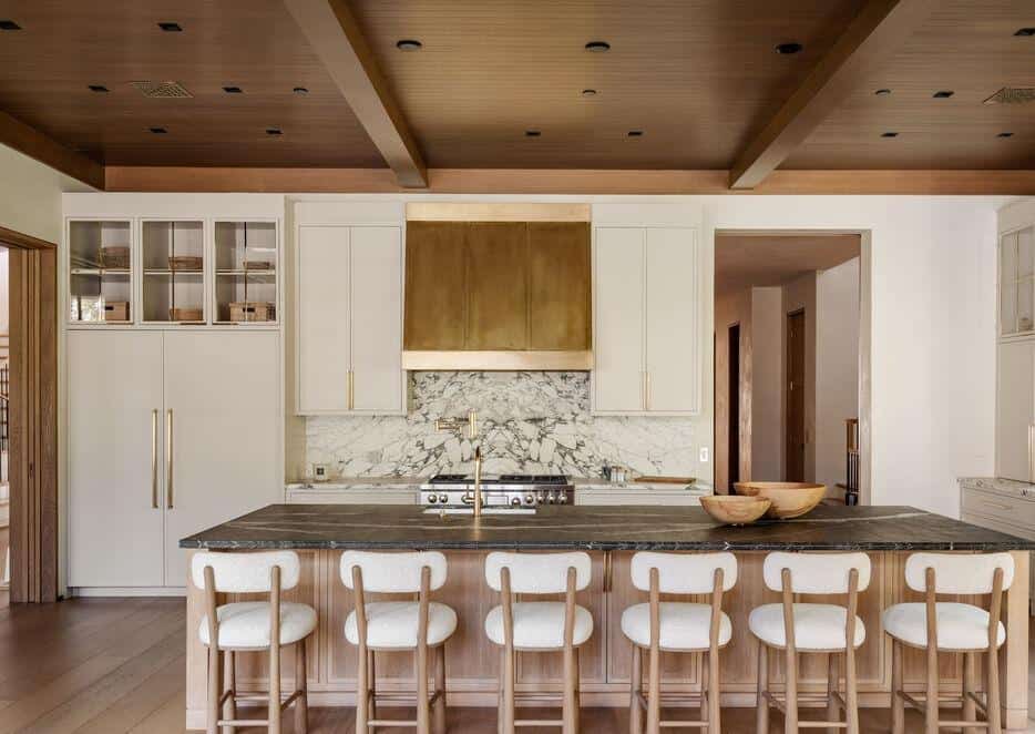 Contemporary kitchen with white cabinets, marble backsplash, and wooden accents.