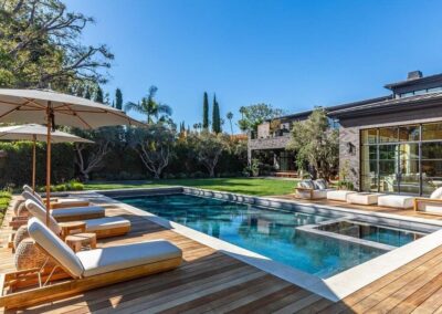 Modern outdoor pool with lounge chairs and lush greenery at Riviera Development Partners.